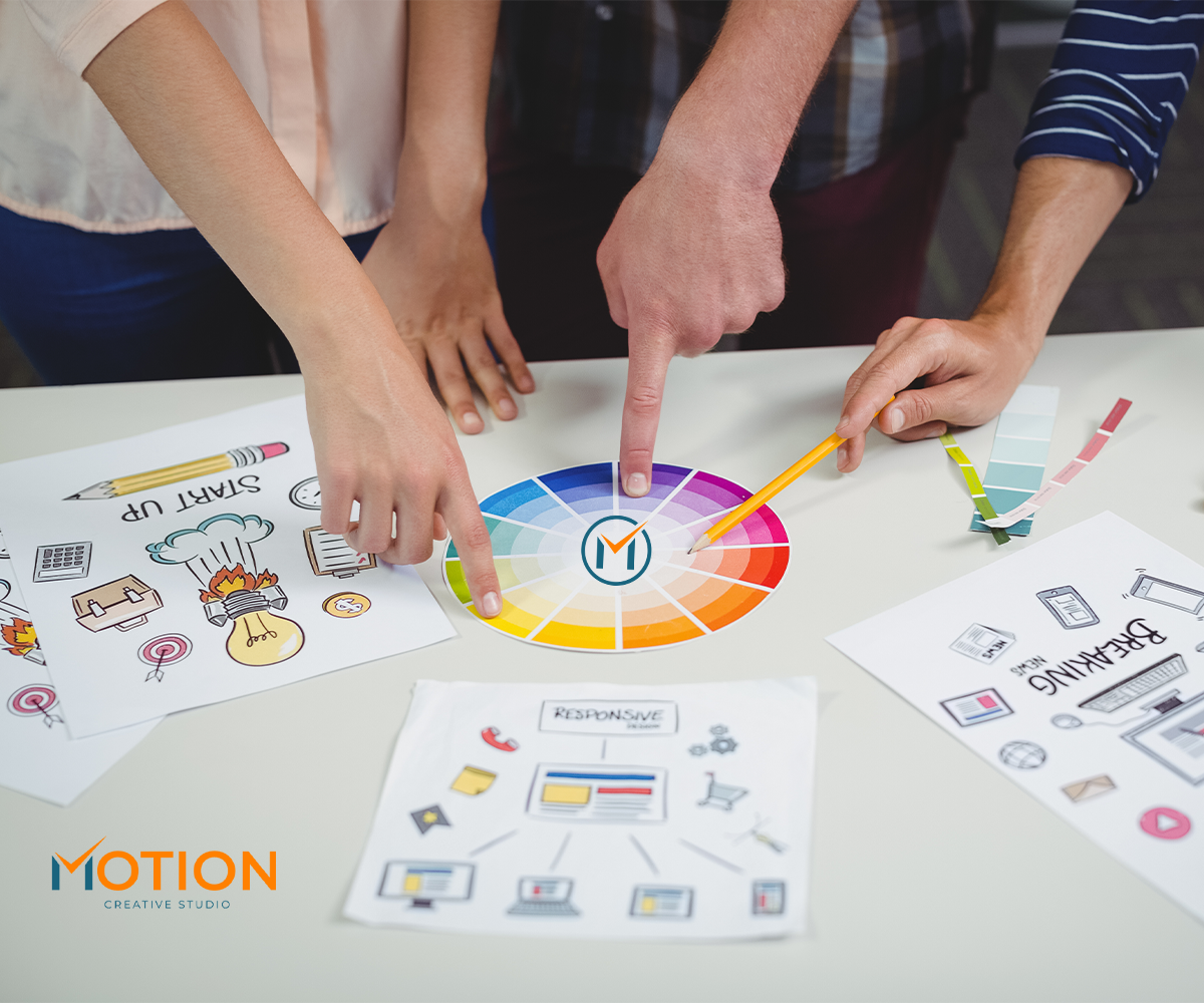 Hands arranging a color palette and branding design samples on a table